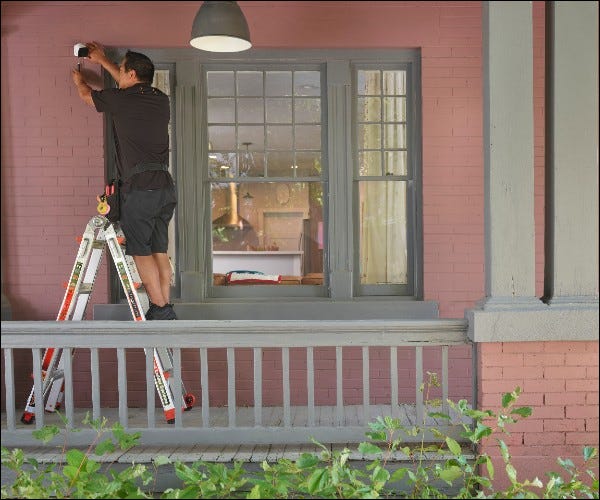 Homem instalando câmera do lado de fora de casa