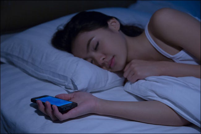Uma mulher dormindo enquanto segura um smartphone.