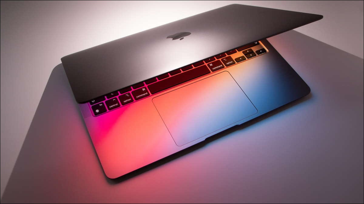 macbook ligeiramente aberto para iluminar o teclado e a mesa