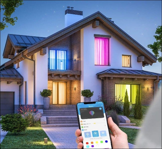 Pessoa usando o aplicativo fora de casa com luzes coloridas nas janelas