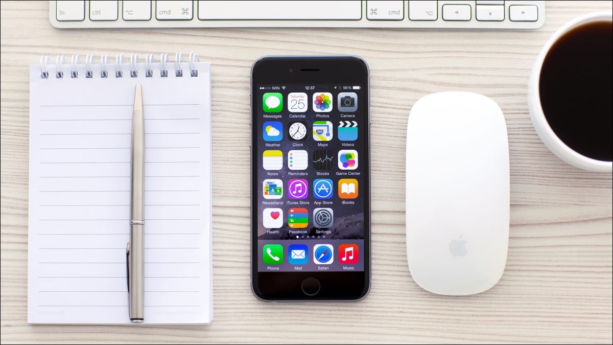 Um iPhone ao lado de um mouse e teclado sem fio.