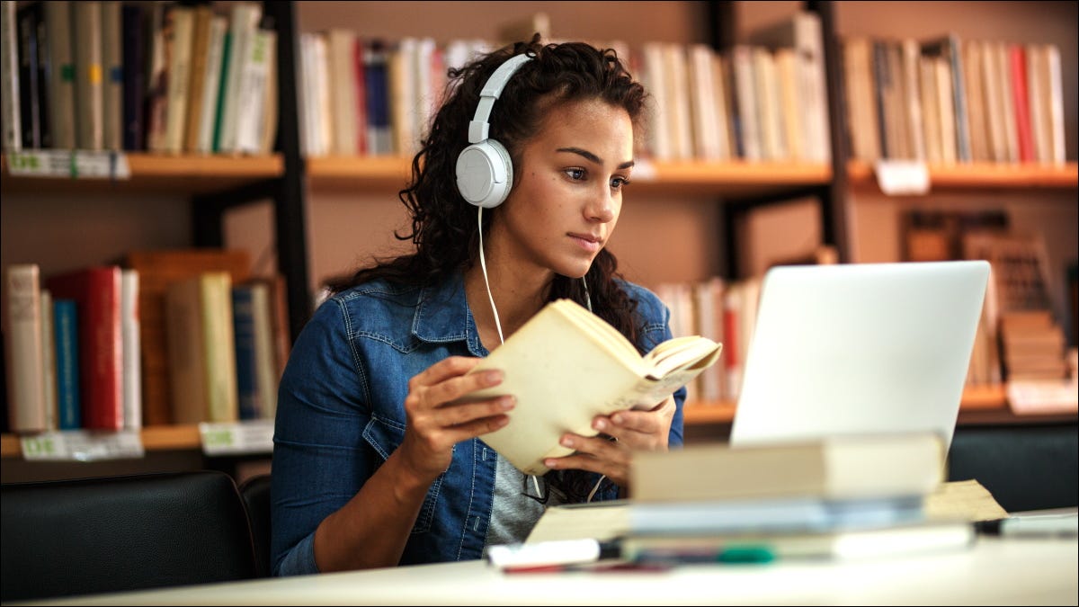 Um aluno estudando em um laptop em uma biblioteca.