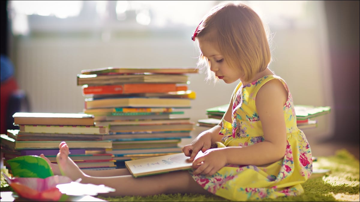 Menina lendo um livro na frente de uma grande pilha de livros