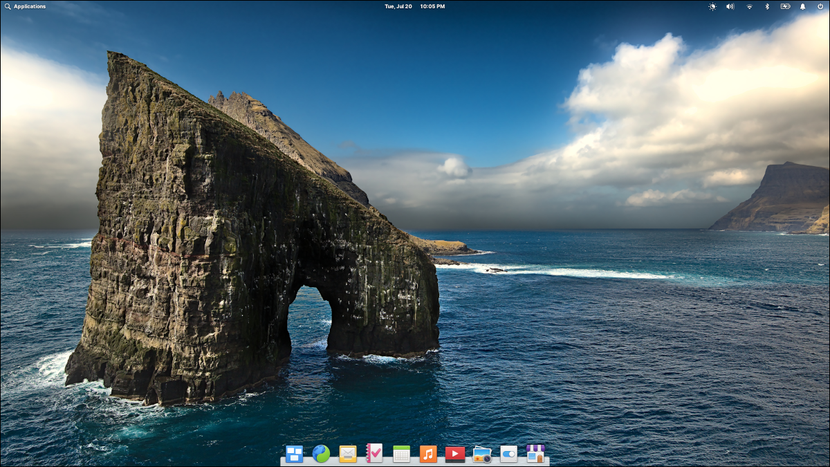 Desktop OS 6 elementar com papel de parede apresentando uma rocha em forma de ferradura no mar.