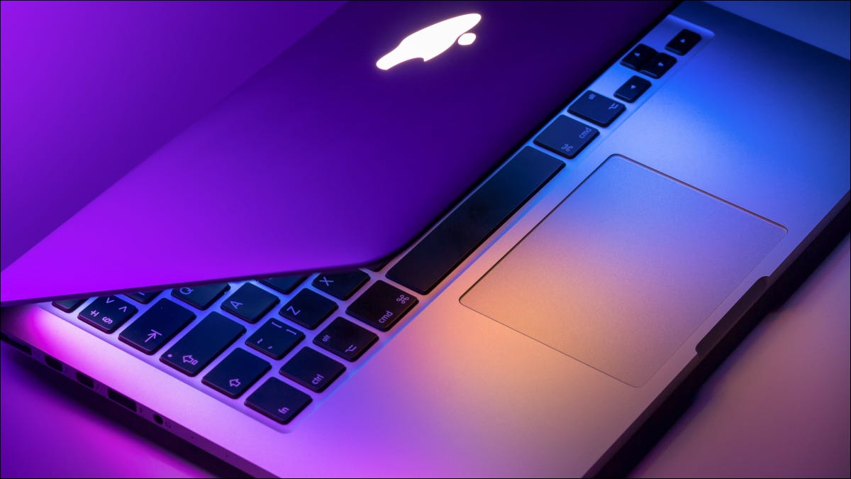 MacBook Pro parcialmente aberto em luzes roxas e azuis