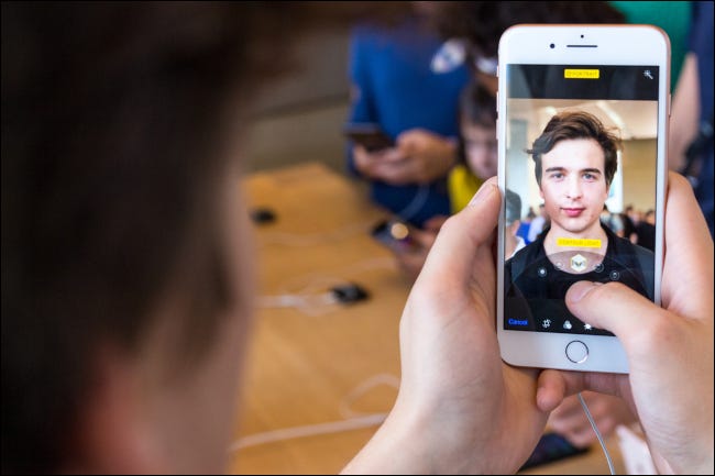 Close do rosto de um homem sendo refletido de volta para ele em um iPhone com modo retrato