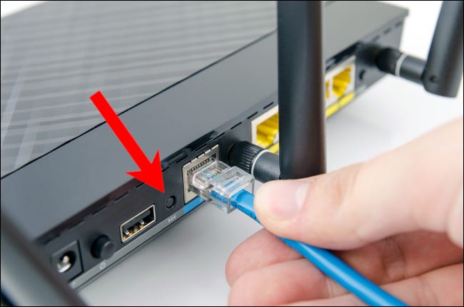 Seta vermelha apontando para o botão reset em um roteador de rede doméstica