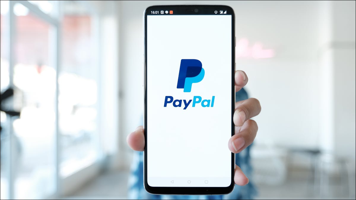 Mão segurando smartphone com exibição do logotipo do PayPal