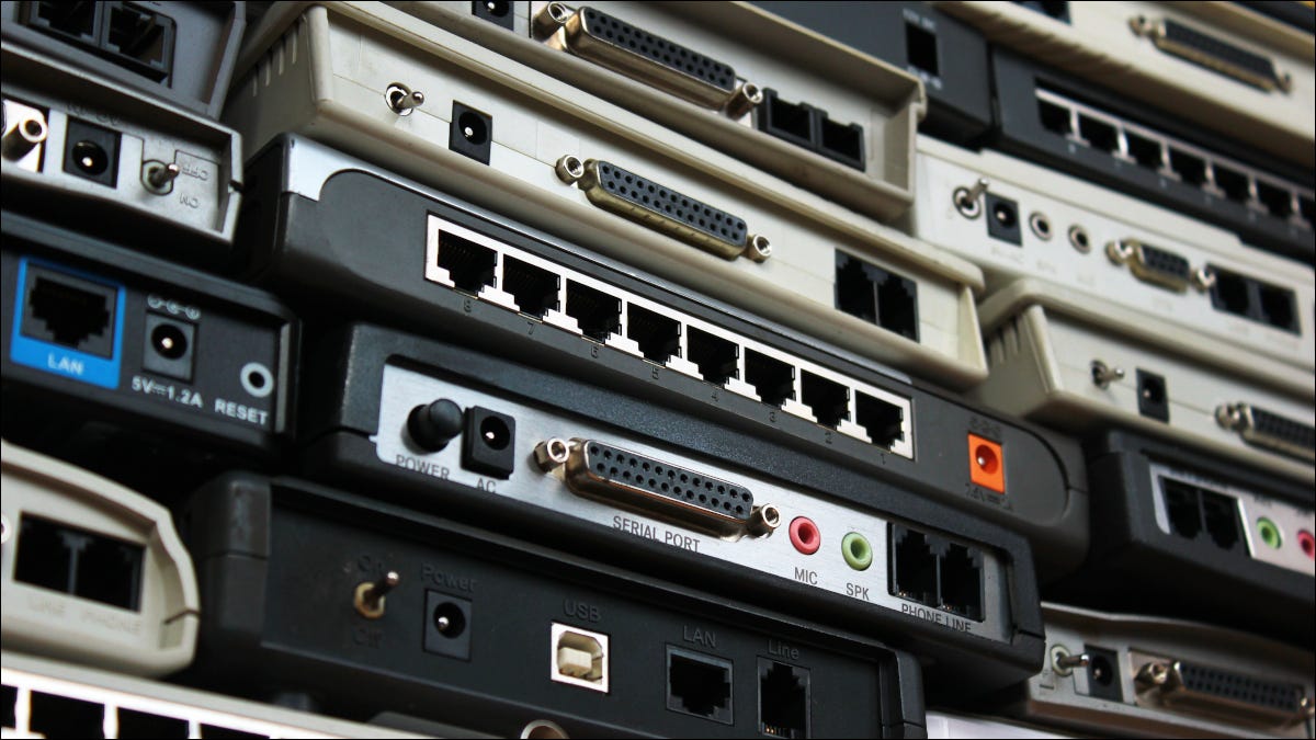 Close de uma parede de modems e roteadores de rede antigos