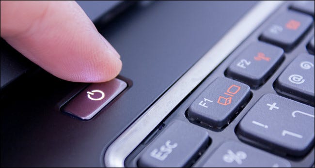 Um dedo apertando o botão liga / desliga do laptop.