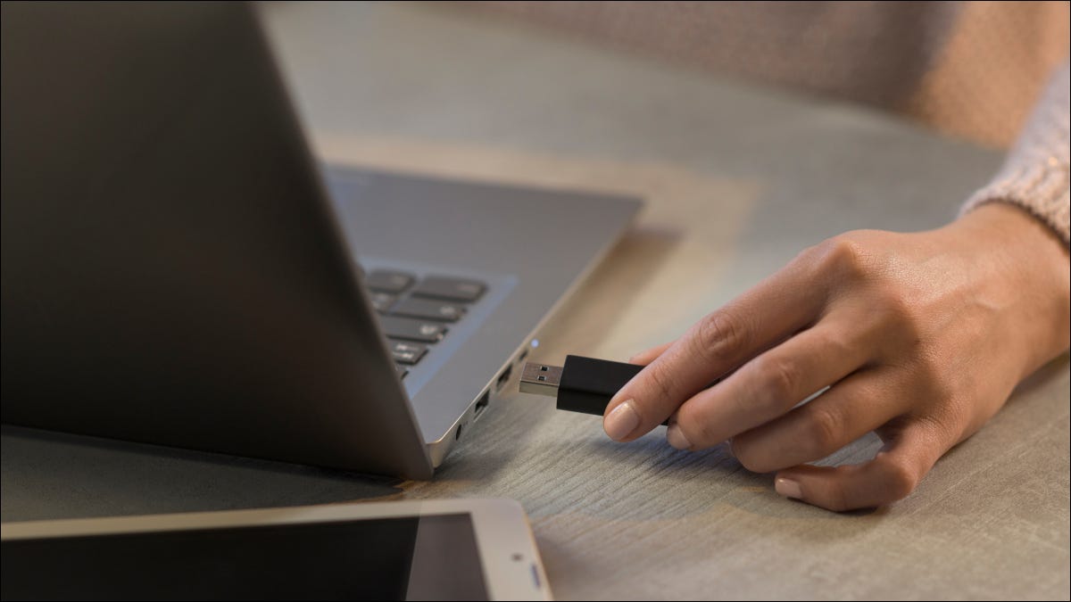 Mão de uma mulher conectando uma unidade USB em um Macbook