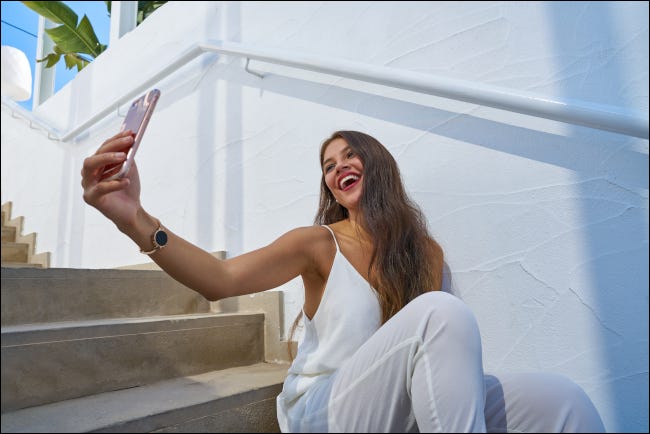 Jovem latina sorrindo e olhando para cima para tirar uma selfie