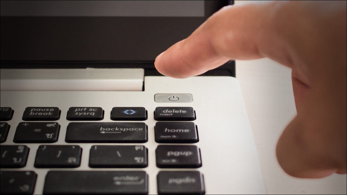 Um dedo prestes a pressionar o botão liga / desliga do laptop.