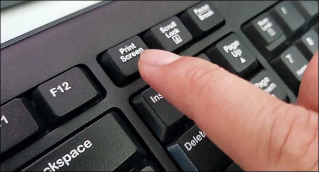 Um dedo pressionando a tecla Print Screen em um teclado.