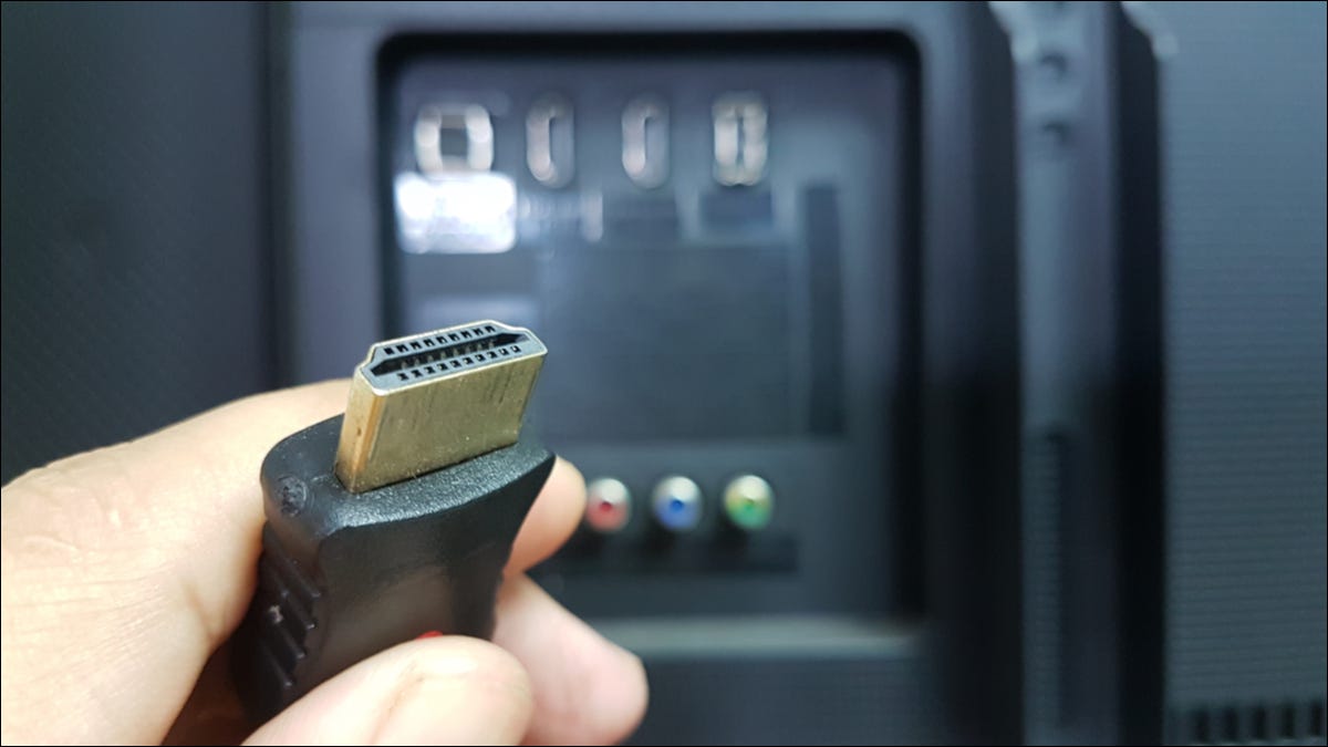 Uma mão segurando um cabo HDMI.