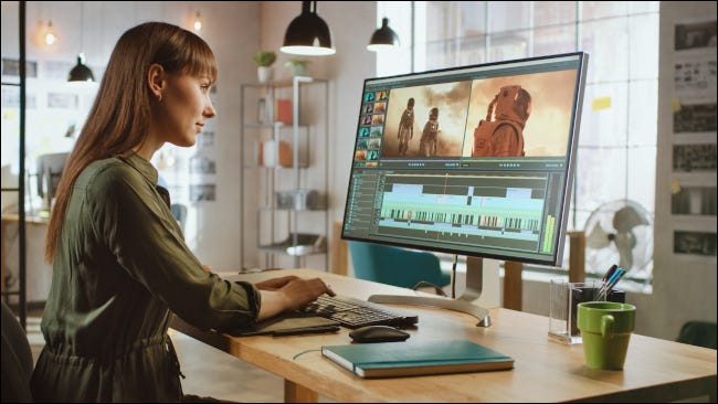 Mulher editando vídeos em um grande monitor de computador