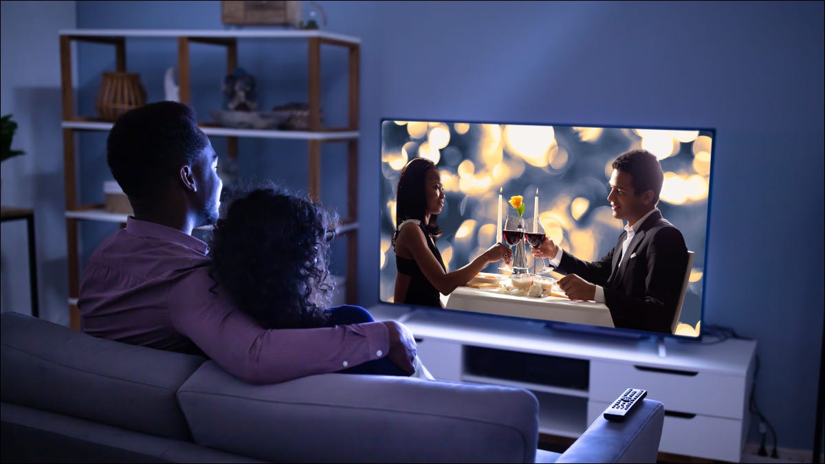 Jovem casal assistindo a um filme em uma grande TV em uma casa moderna