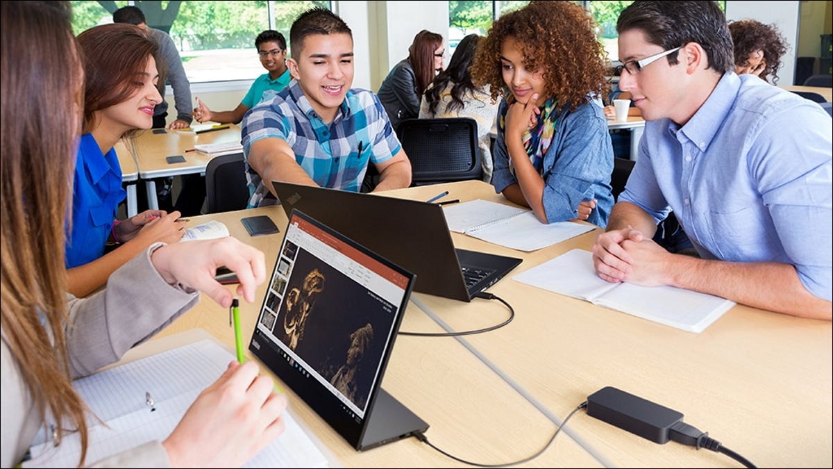 students gathered around laptop with lenovo portable monitor