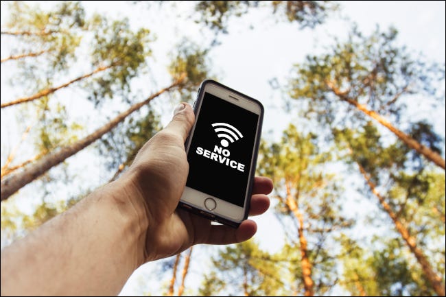 Mão segurando o smartphone contra árvores com a mensagem "Sem serviço" em exibição