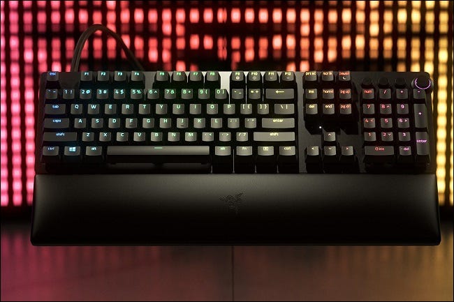 Razer Huntsman V2 com luzes rosa e amarelas no fundo