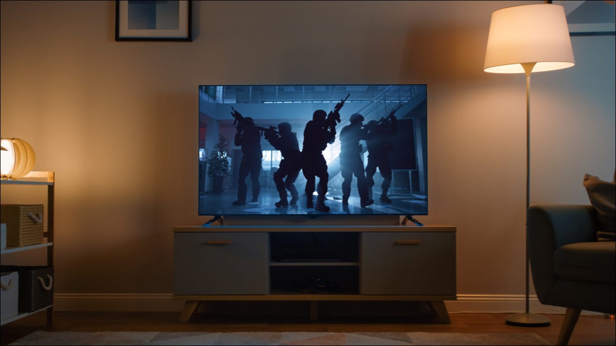 Uma TV exibindo um filme de ação sombria em uma sala de estar.