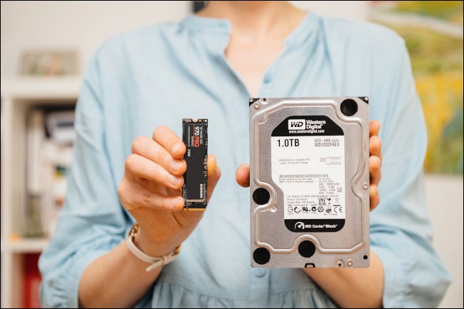 Mulher segurando uma unidade NVME e HDD.