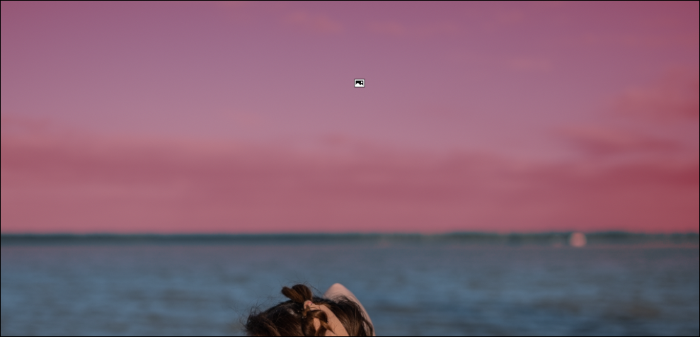 Imagem recortada que mostra um lago, o horizonte e o céu.  O céu está coberto de vermelho.