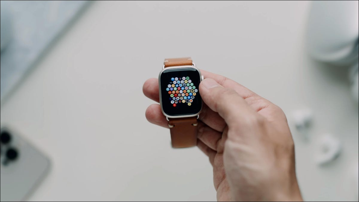 Mão segurando um Apple Watch Series 7 com uma pulseira de couro.