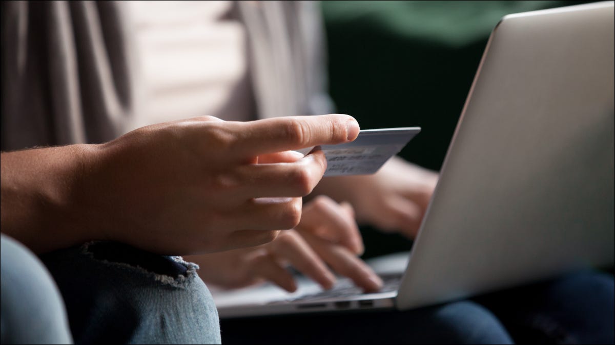 Casal fazendo compras online com laptop e segurando um cartão de crédito