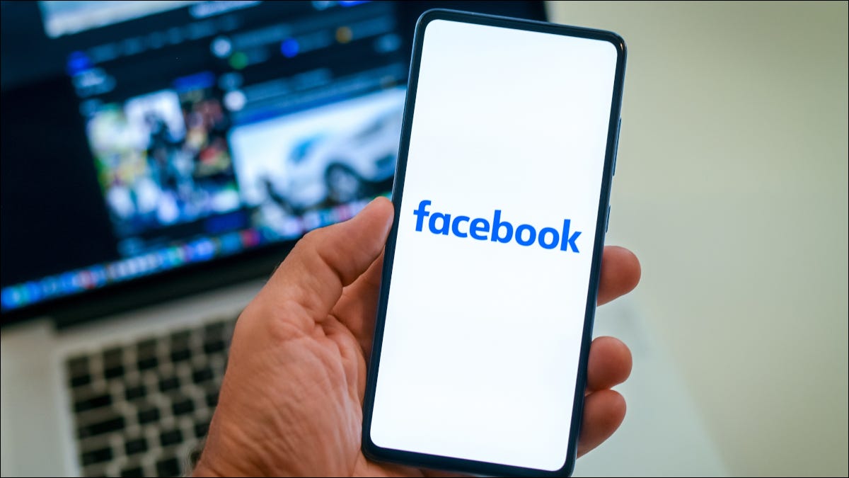 Logotipo do Facebook em um smartphone acima de um laptop mostrando o perfil do Facebook