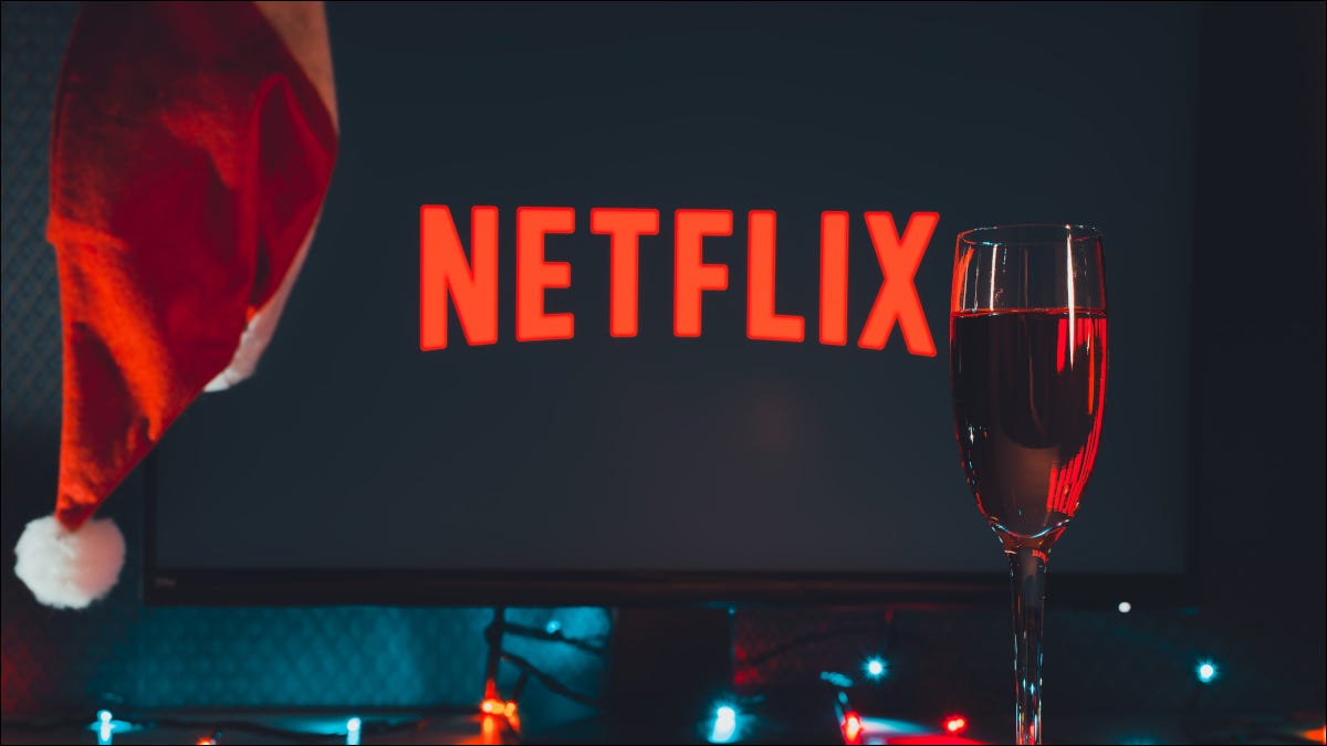 Logotipo da Netflix em uma tela de TV com um chapéu de Papai Noel e taça de champanhe