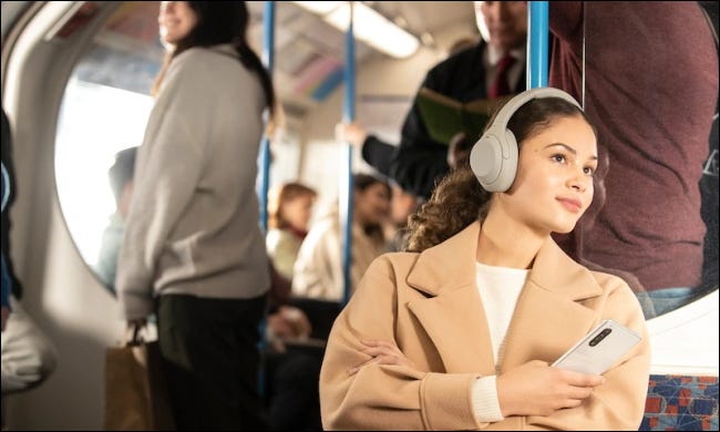 mulher usando Sony XM4s no ônibus