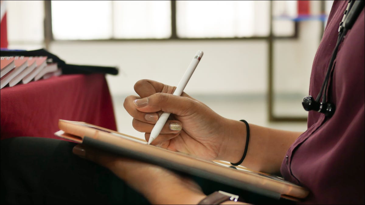 Close das mãos de uma mulher desenhando em um tablet com um lápis