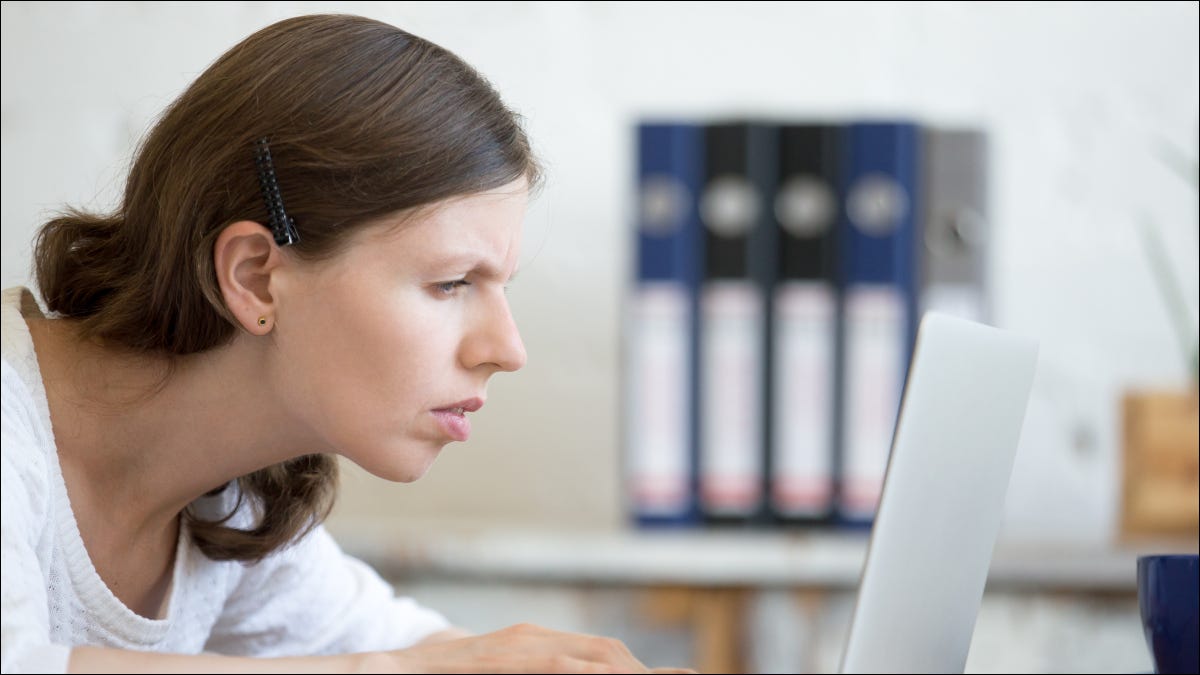 Mulher olhando com uma expressão estressada ou concentrada para a tela de um laptop