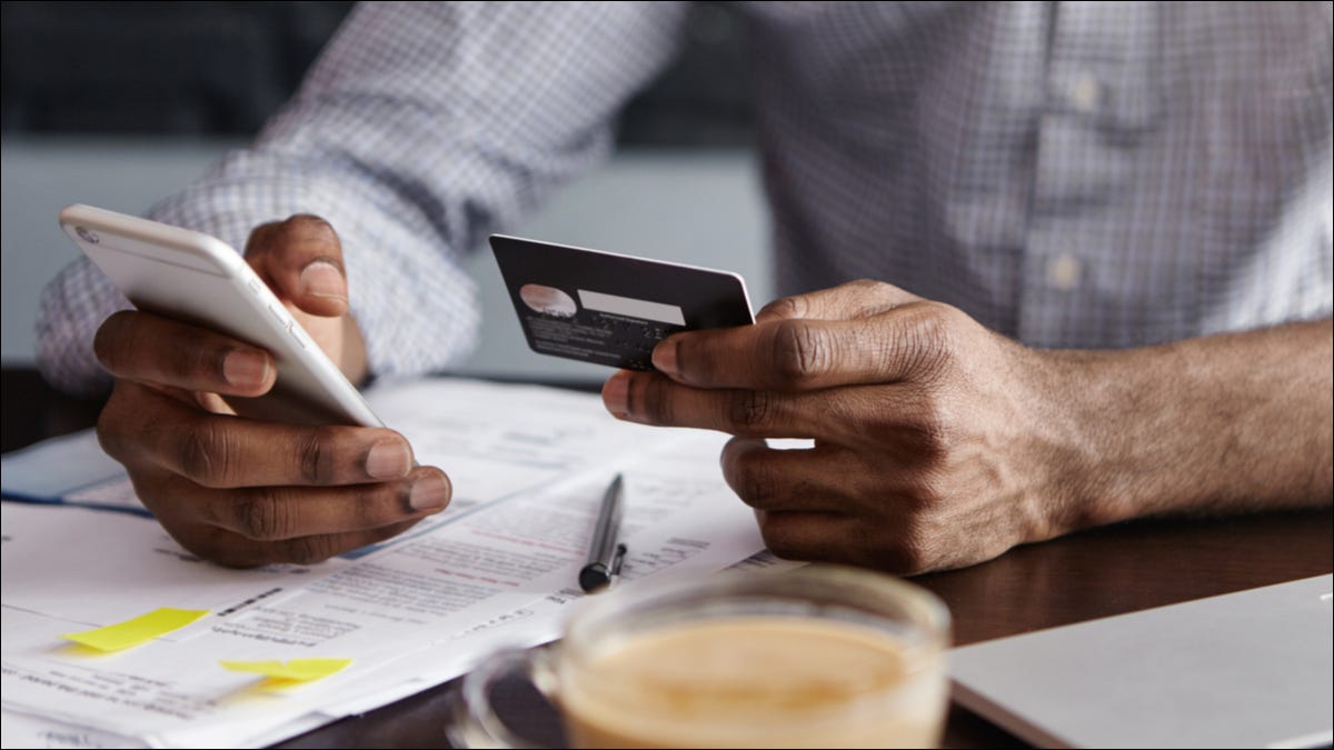 Um homem bancário em um telefone com um cartão de crédito na mão