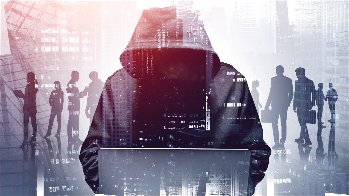 Um hacker anônimo vestindo um capuz, agachado sobre um laptop.