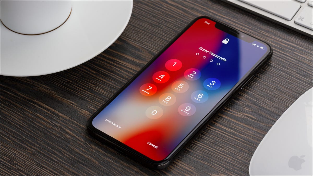 Um iPhone X em uma área de trabalho cercado por periféricos da Apple e mostrando a entrada do PIN.