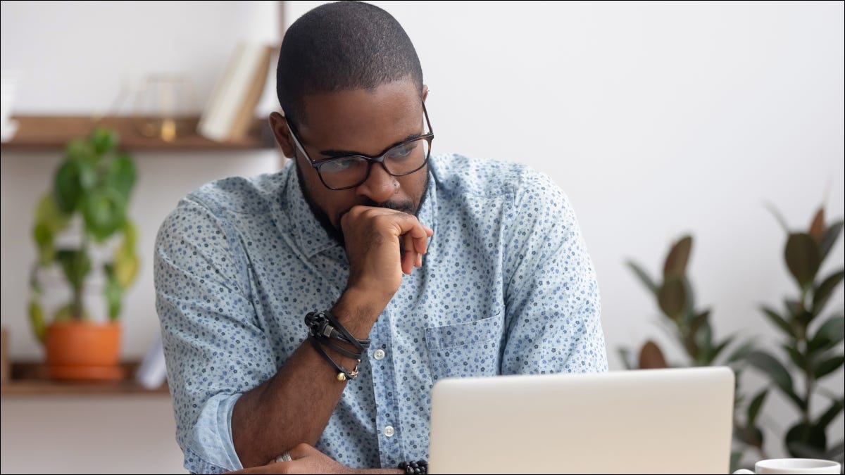 Um jovem olhando para uma tela de laptop com uma expressão confusa.