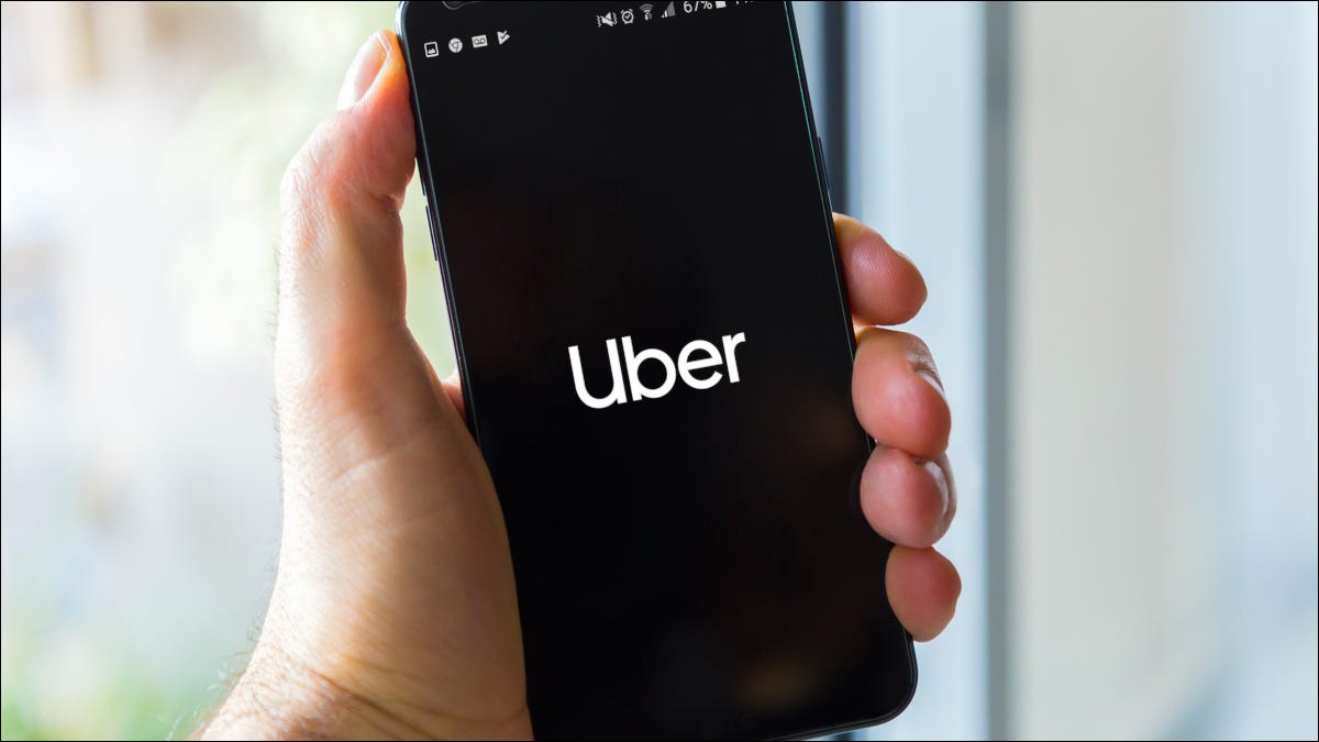 Uma mão segurando um smartphone exibindo o logotipo da Uber.