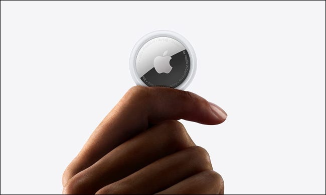 Uma Apple AirTag nos dedos de uma pessoa.