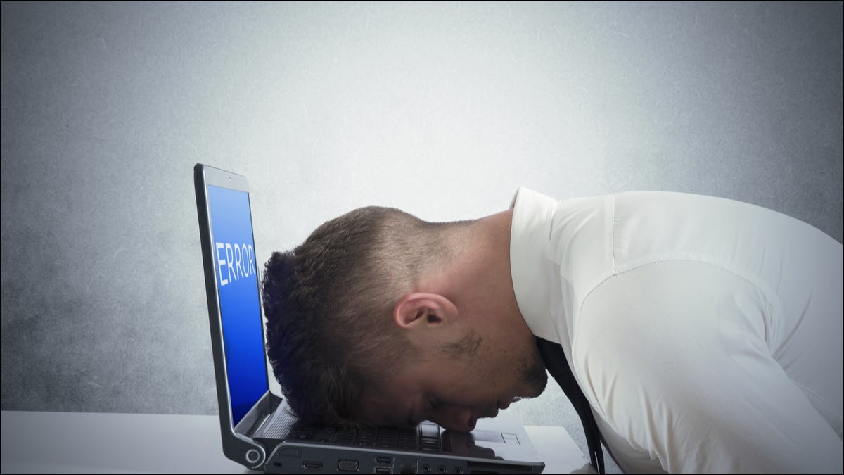 Um homem descansando a cabeça em um laptop com um erro