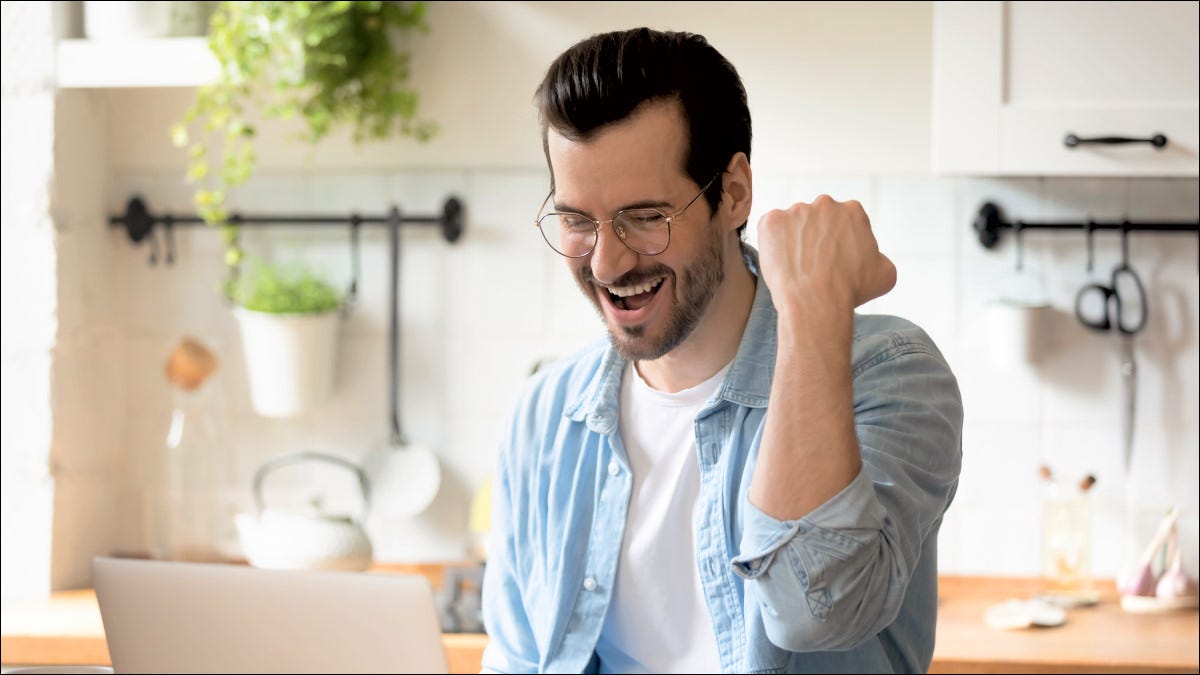 Um homem comemorando na frente de um computador.