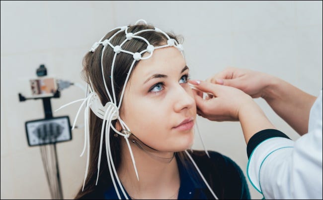 Um médico anexando eletrodos à cabeça de um paciente.