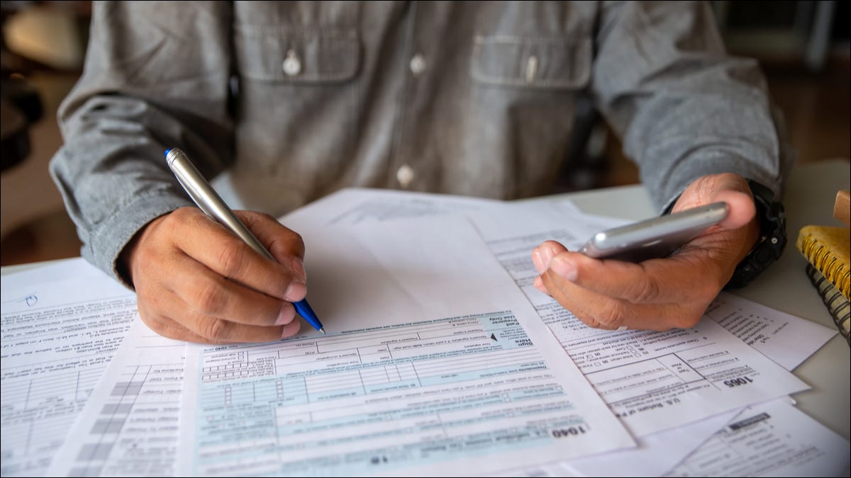 Pessoa fazendo impostos à mão com um formulário 1040.