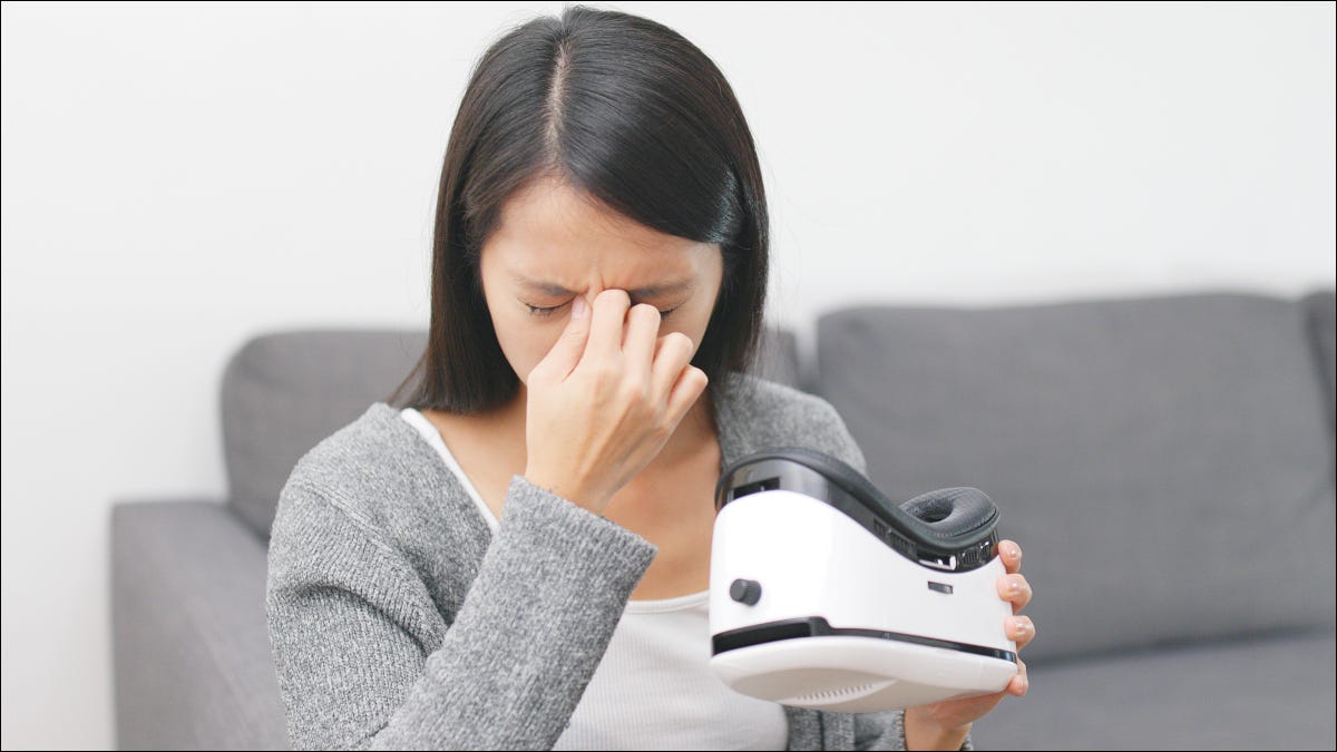 Mulher tocando a cabeça com dor depois de tirar um fone de ouvido de realidade virtual.