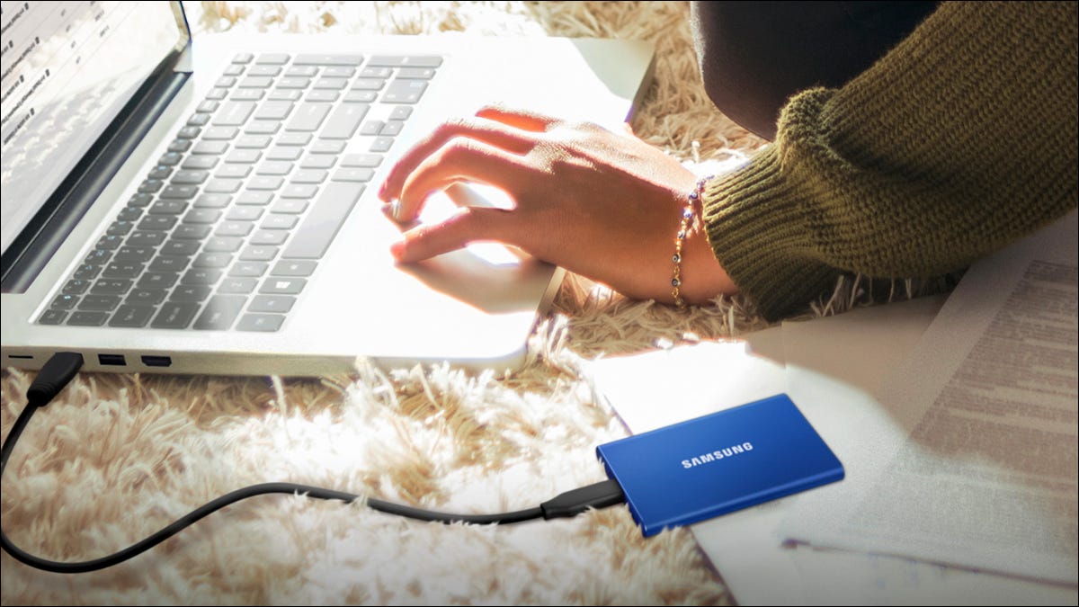 Um SSD externo Samsung no chão ao lado de um laptop