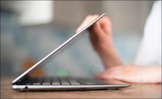 Uma pessoa fechando ou abrindo a tampa de um laptop