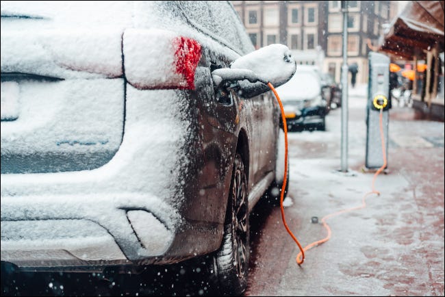 Um carro elétrico estacionado e carregando na neve.