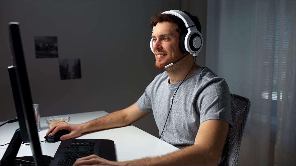 Jogador masculino sorrindo e usando um PC desktop.