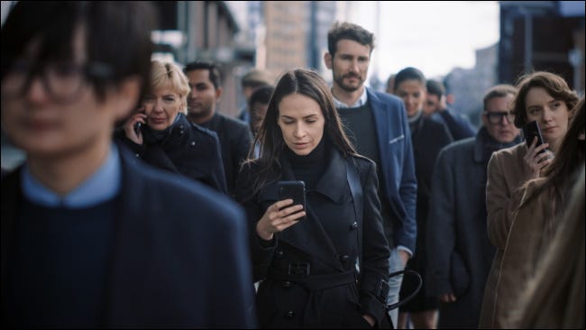 Uma multidão de pessoas usando smartphones em uma rua da cidade.